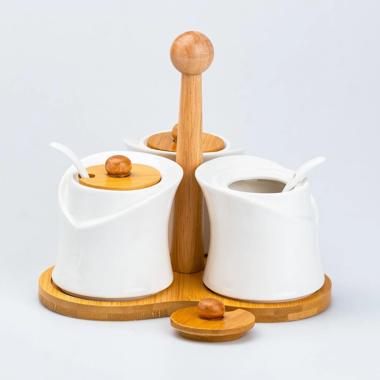 A set of jars for spices 3 pieces with lids and spoons on a stand